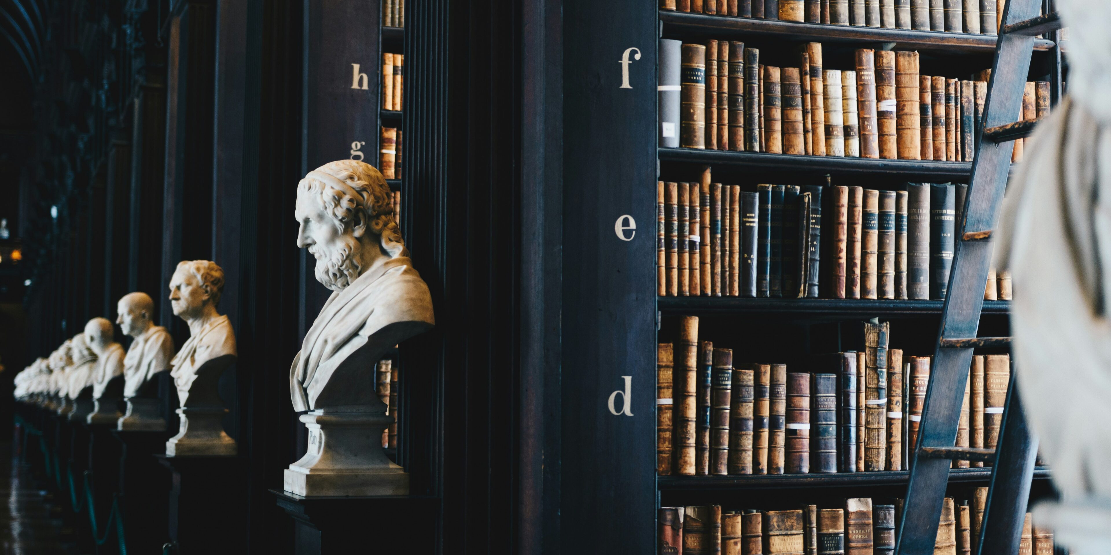 clause-library A bust of a man in front of some books.